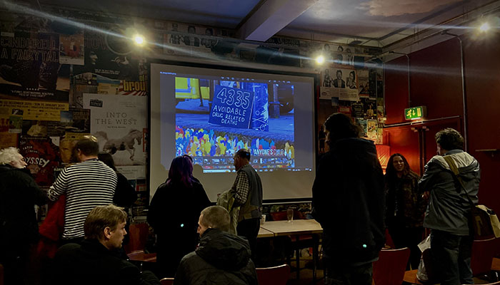 A group of people standing in front of a projector screen