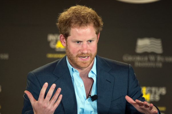 Prince Harry speaking with his hands up in motion.