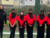 Girls wearing their specially-adapted hijabs on a football pitch.